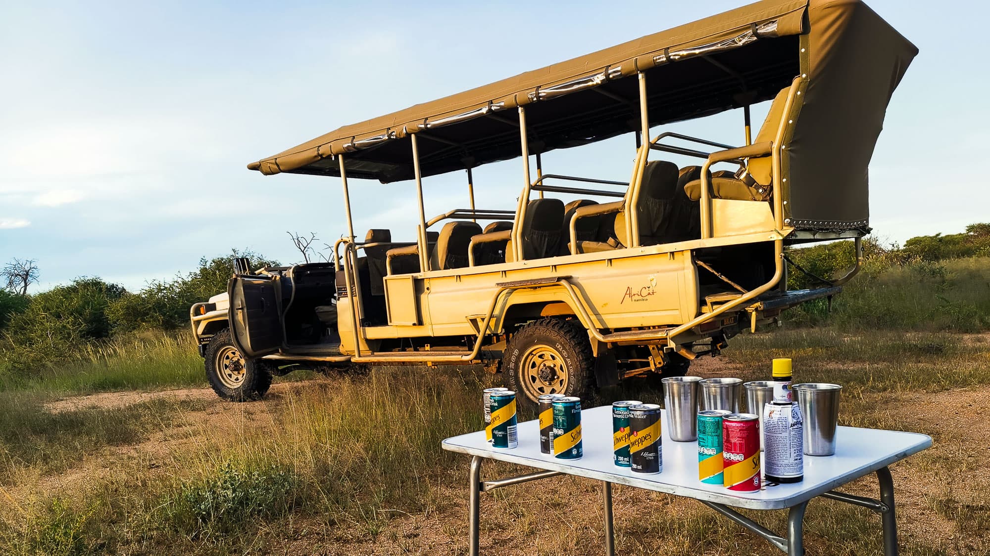 Ein Sundowner mitten im namibischen Busch: Das offene Safarifahrzeug wartet, die Getränke stehen bereit und der Tag darf ganz langsam ausklingen.